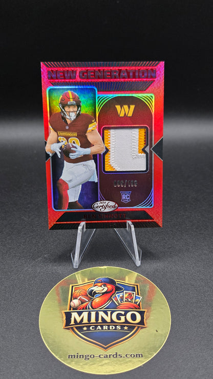 A collectible football trading card displayed on a clear stand next to a round gold Mingo Cards collector's medallion on a dark gray background.
