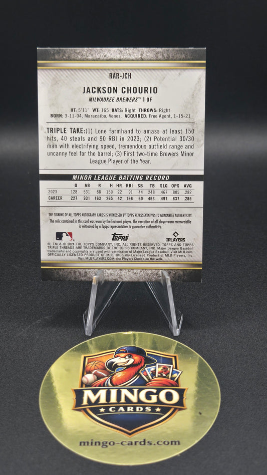 A collectible sports trading card and its circular Mingo Cards display stand on a dark background. The card features baseball player Jackson Chourio with his career stats printed on the back, and the right side shows the round gold-toned Mingo Cards display stand.
