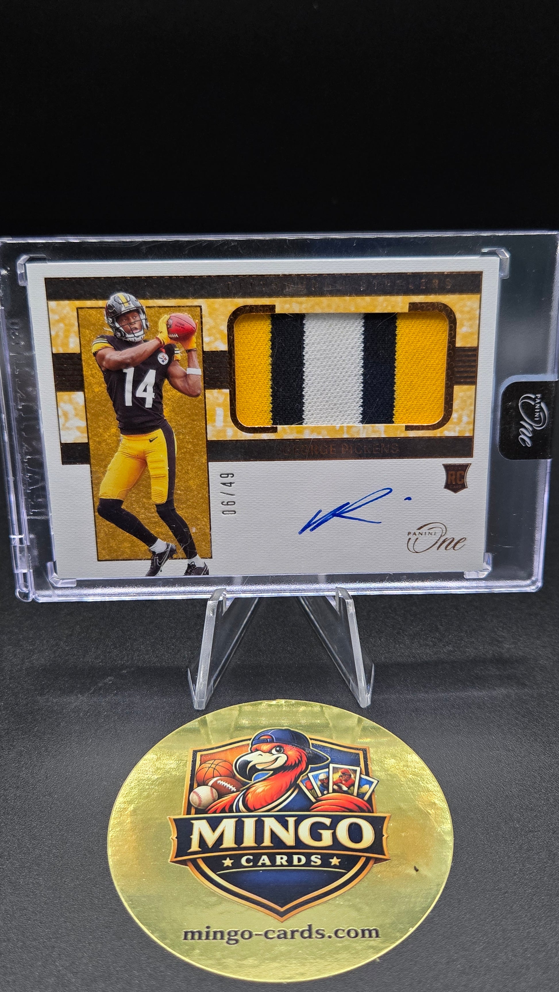 A collectible sports trading card in a clear protective case, displayed alongside a round gold Mingo Cards logo sticker on a black background. The card features a yellow and black jersey swatch, a player photo, and an autograph.