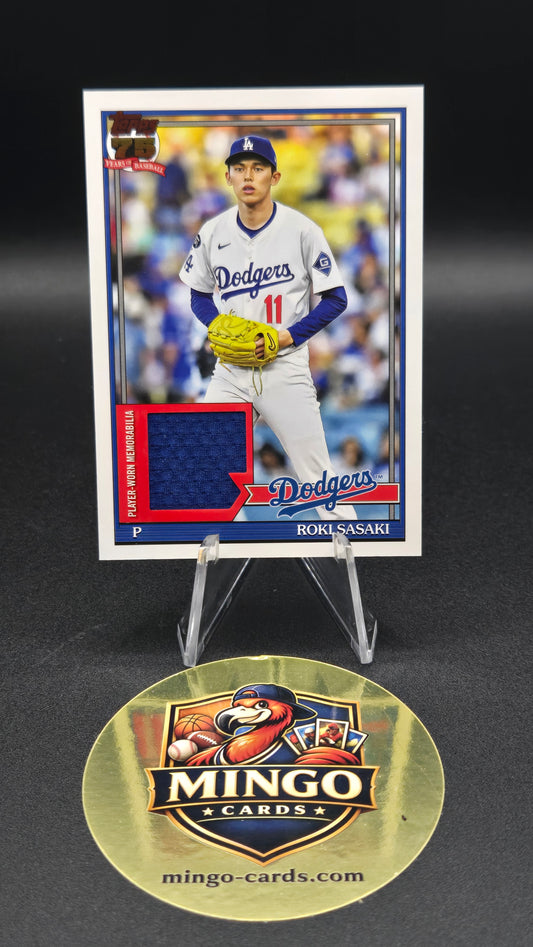 A baseball trading card of Roki Sasaki on a clear display stand next to a round gold Mingo Cards brand medallion on a black background.